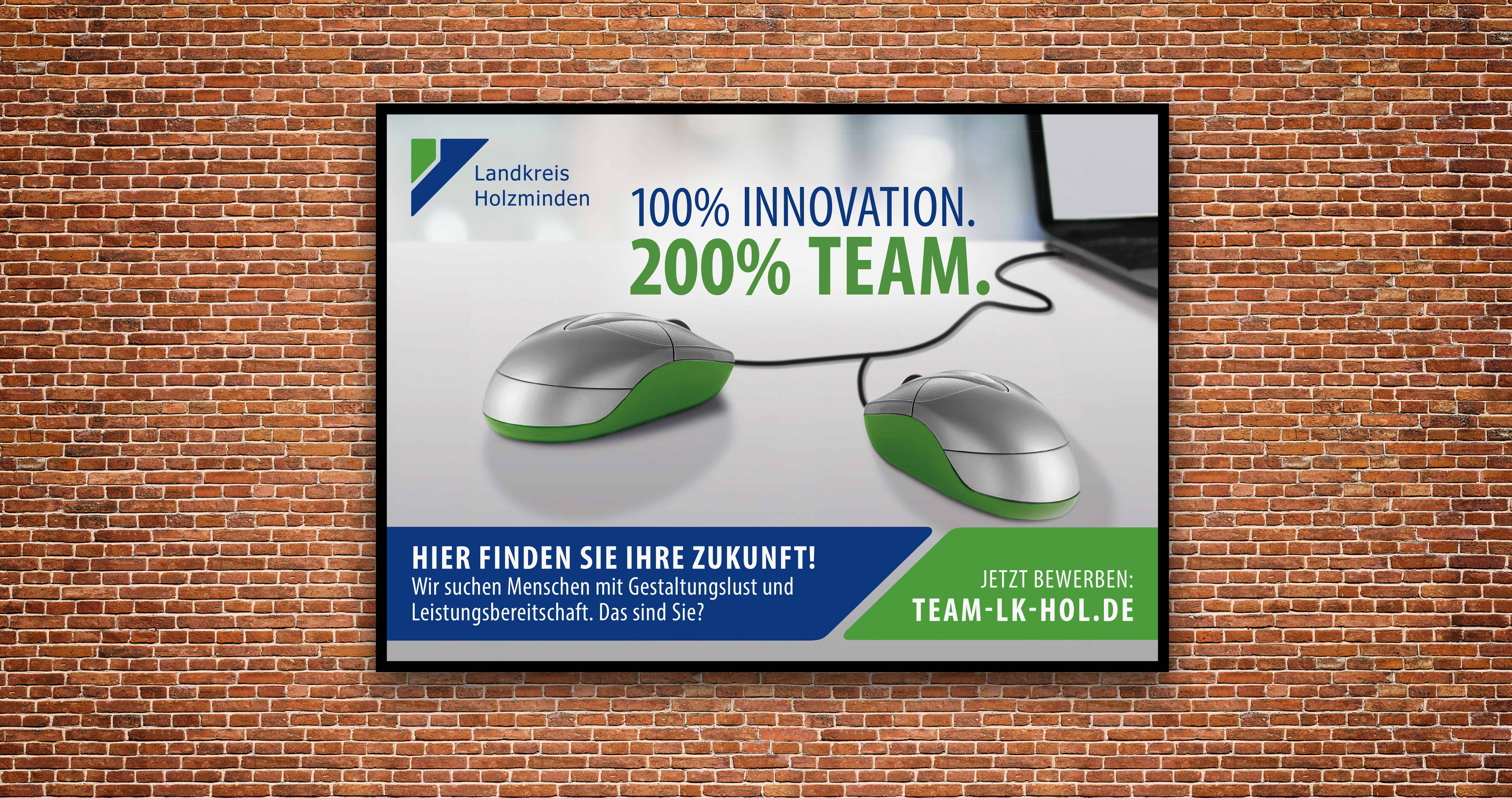 Plakat des Landkreises Holzminden zur Personalgewinnung mit dem Slogan „100 % Innovation. 200 % Team.“ an einer Backsteinwand.