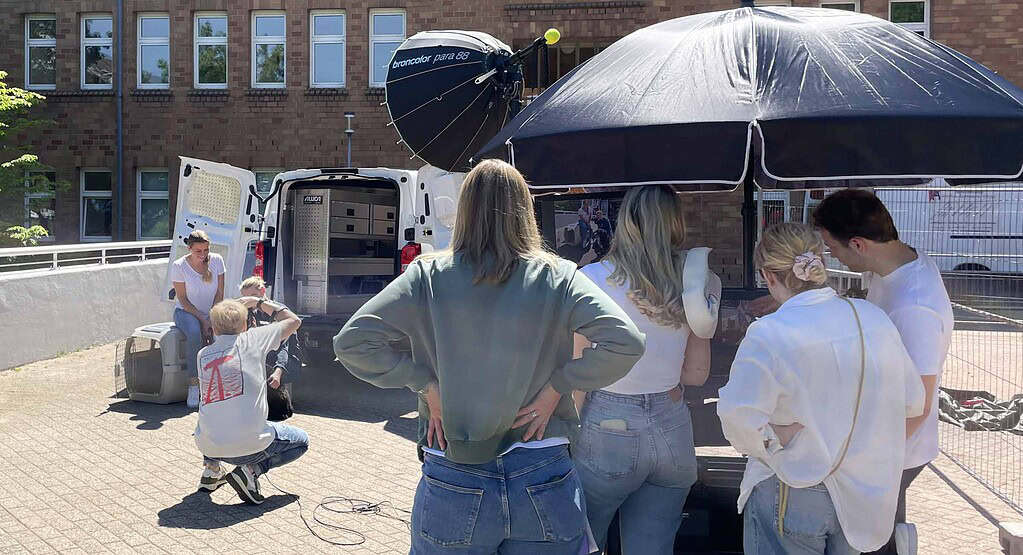 Behind-the-Scenes bei einem Fotoshooting im Außenbereich mit Fotograf, Beleuchtungsequipment und Produktionsteam.